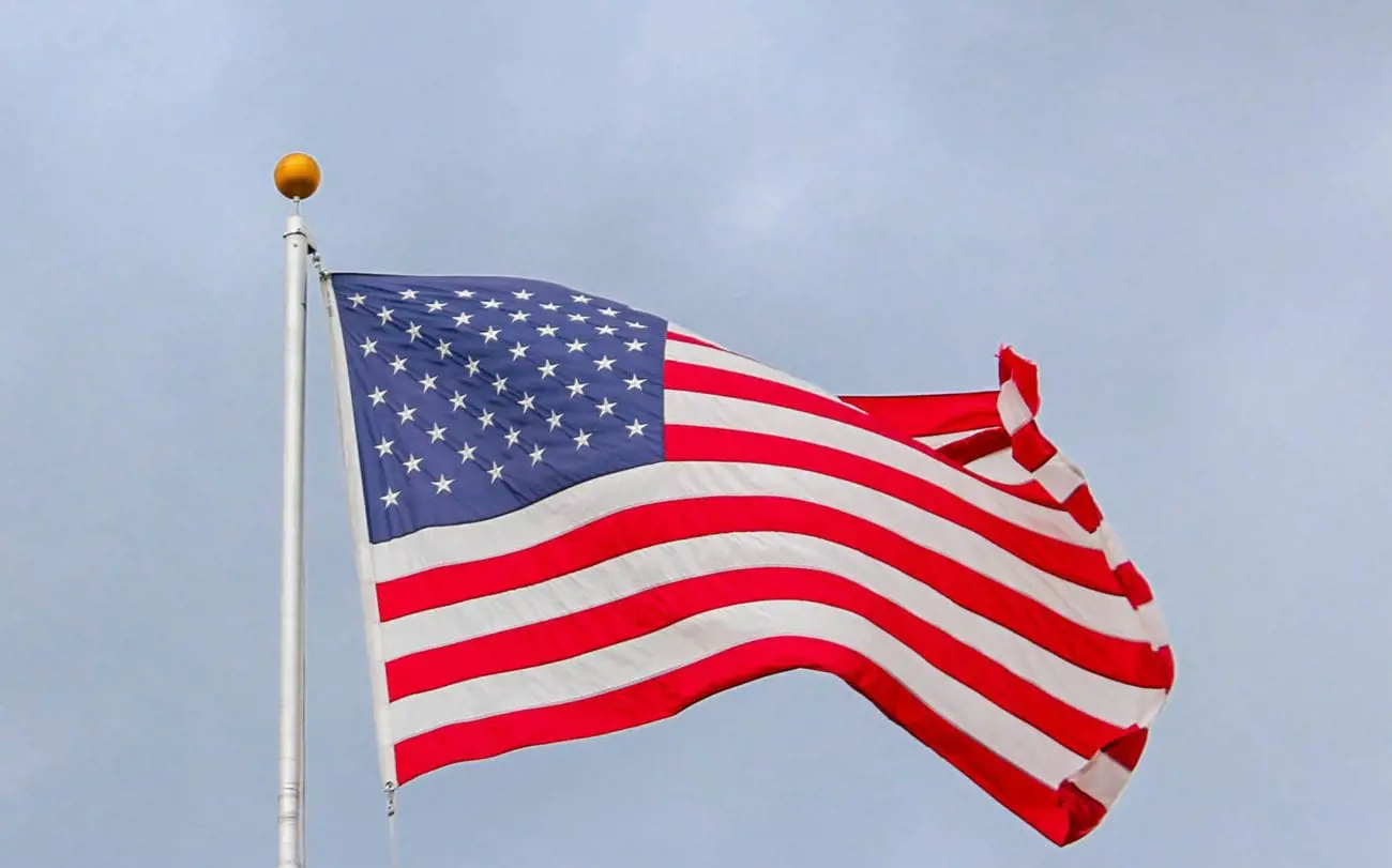 usa-flag-waving-on-white-metal-pole-15503424